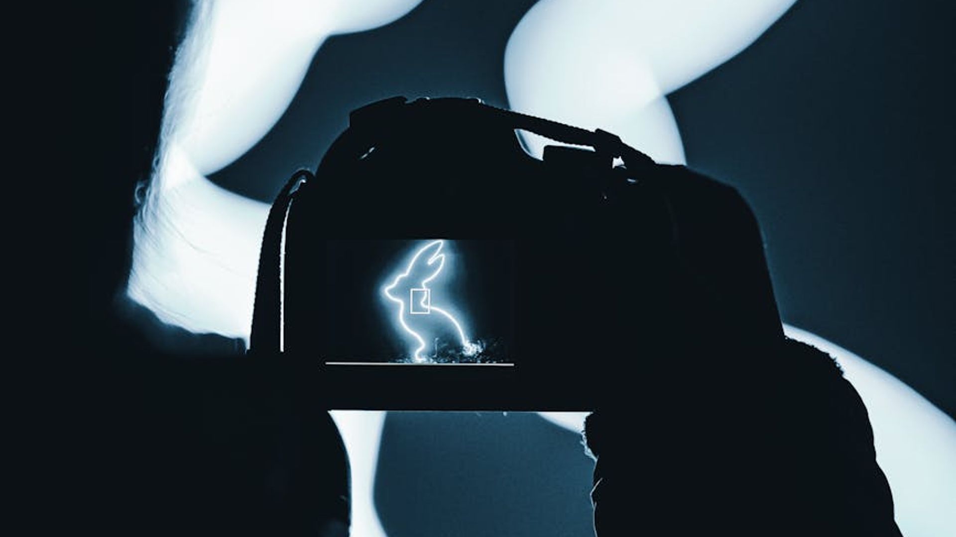 Silhouette of a person in a dynamic pose against a dark background with red light trails.